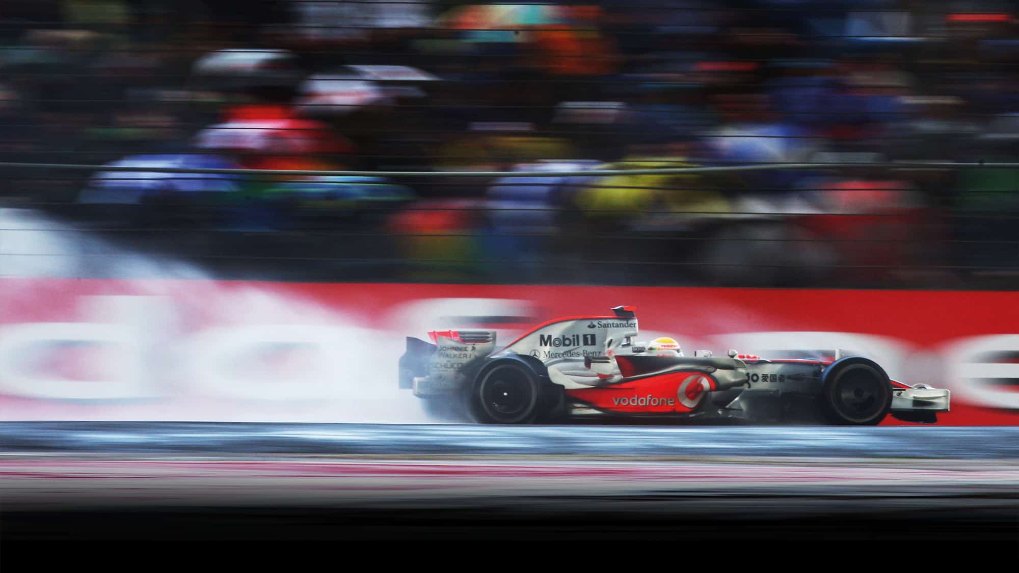 Lewis Hamilton creating a cloud of spray as he races to victory ona. wet Silverstone track in the 2008 F1 British Grand Prix